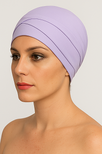 A woman wearing a lilac headscarf poses against a neutral background, showcasing a stylish and elegant head wrap.
