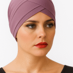A person wearing a stylish, lavender headscarf with a sleek design and a black top, set against a plain white background.