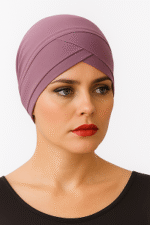 A person wearing a stylish, lavender headscarf with a sleek design and a black top, set against a plain white background.